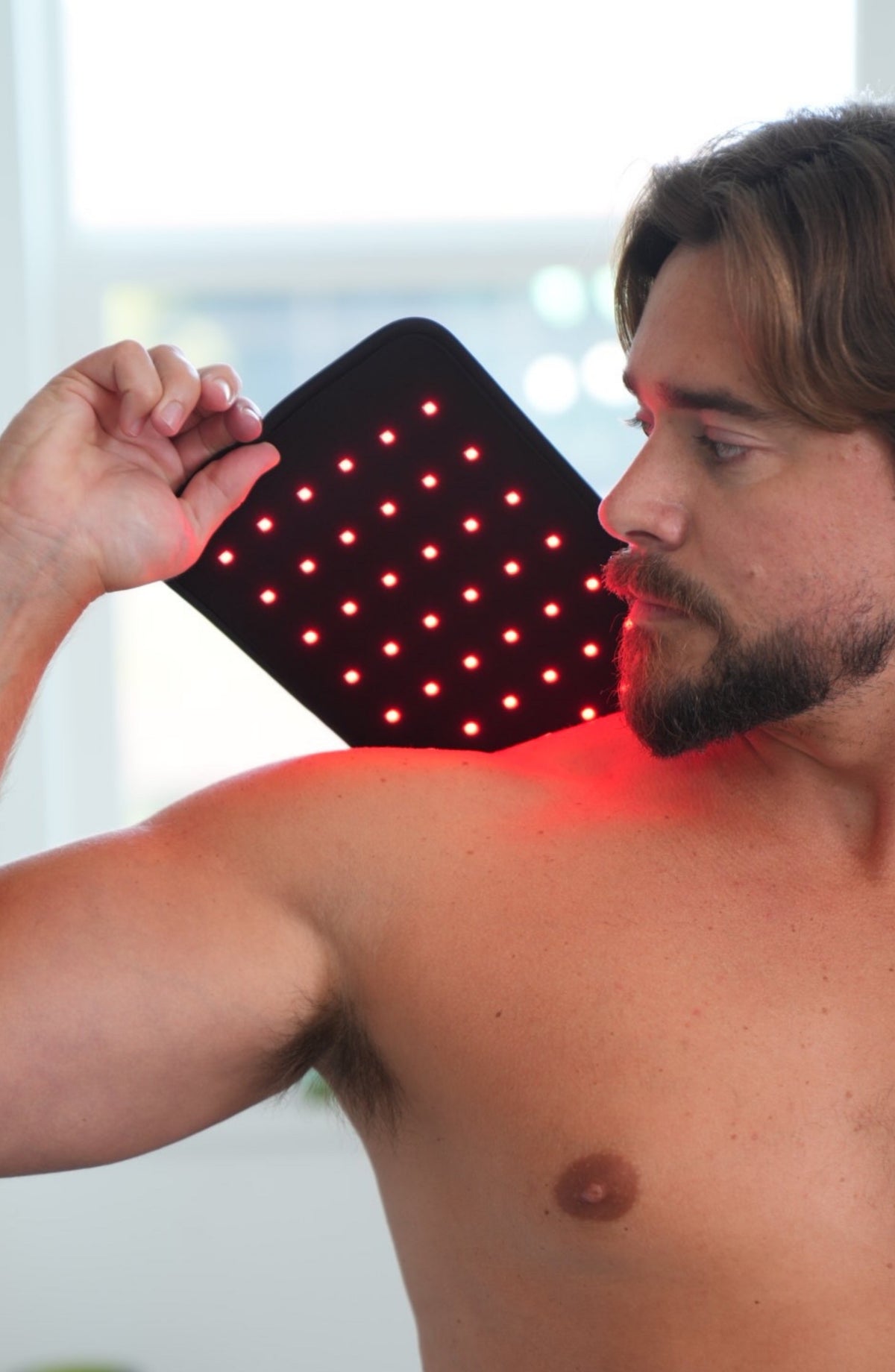 Man holding a lit Fringe Heals red light wrap against his shoulder