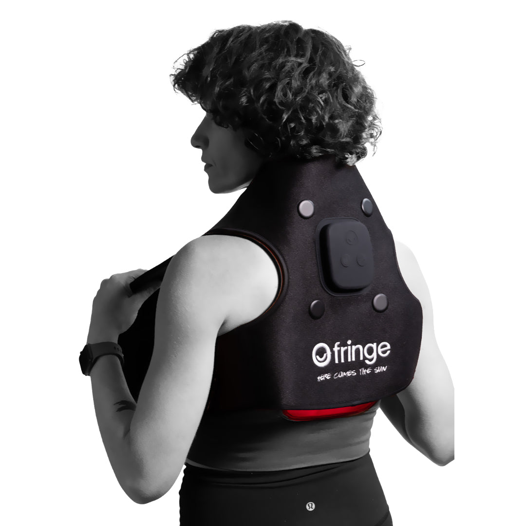 Fringe red light therapy neck and shoulder wrap worn by a person.