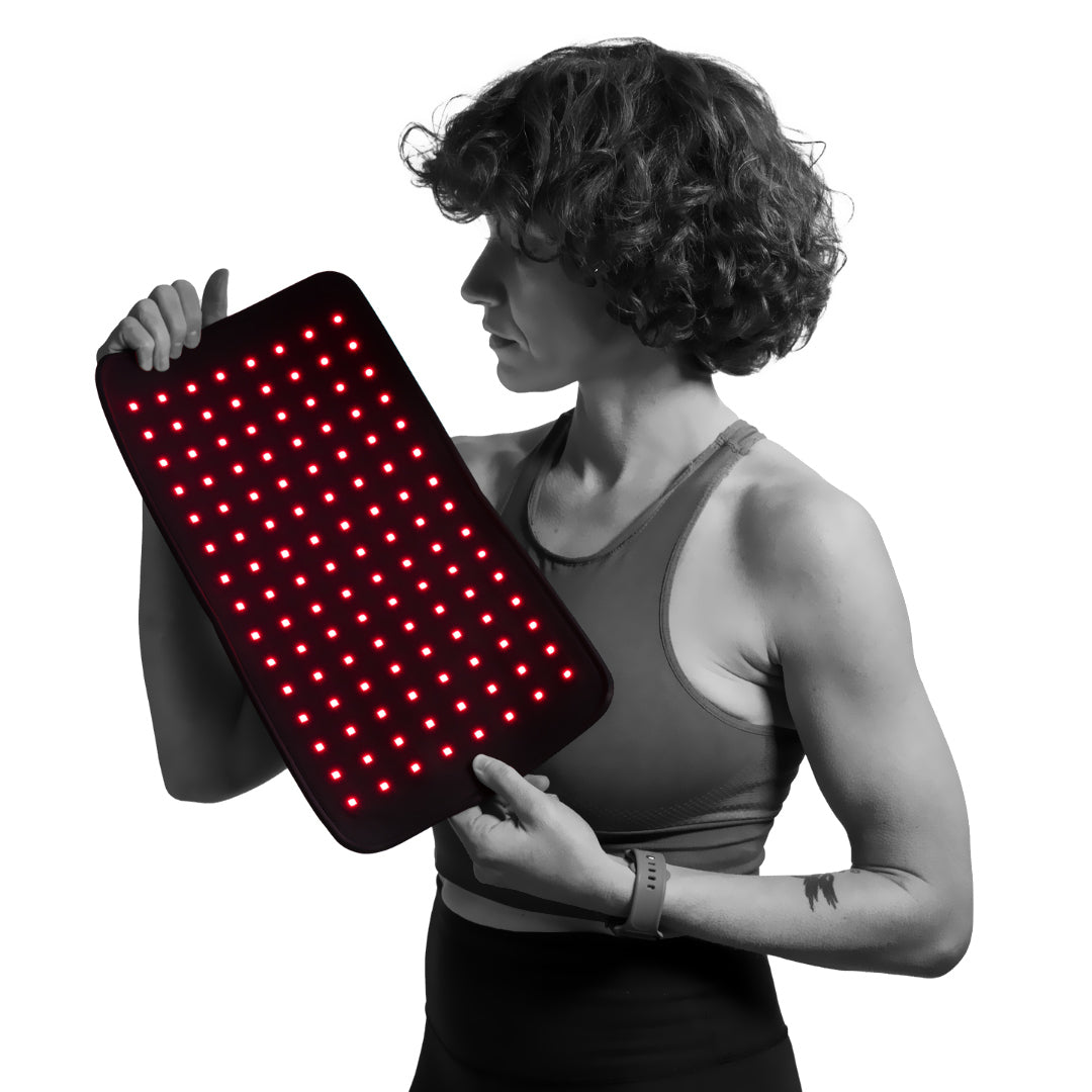 A woman holds a Fringe red light therapy wrap with numerous red LEDs illuminated.